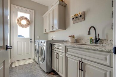 Laundry room has deep sink and upgraded cabinets with granite countertops.