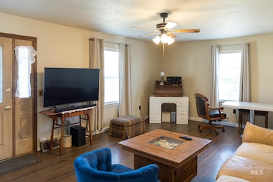 Living area featuring a desk, dark wood-style flooring, and ceiling fan