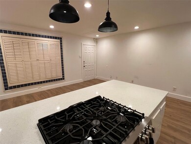 Kitchen featuring recessed lighting, dark wood-style flooring, light stone counters, hanging light fixtures, and gas stove