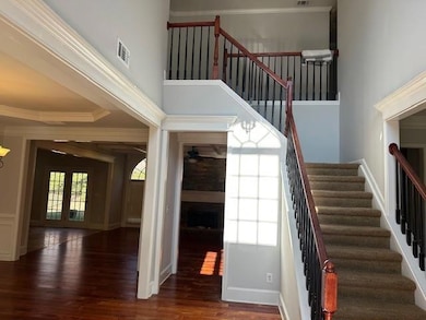 Staircase with wood finished floors, a fireplace, crown molding, a towering ceiling, and french doors