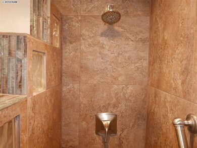 Bathroom has a shower with a ceramic tile and glas