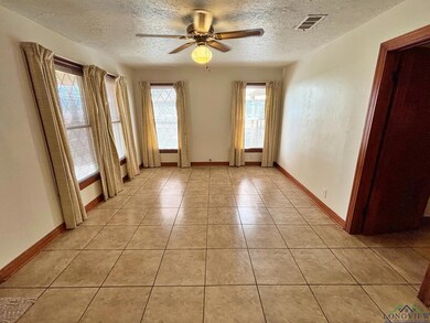 Unfurnished room featuring a textured ceiling, a ceiling fan, light tile patterned flooring, and baseboards