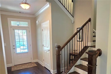 Foyer entrance with ornamental molding, dark wood style finished flooring.