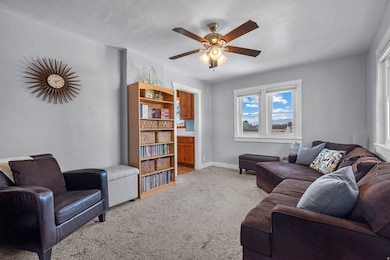 Living area with light colored carpet and a ceiling fan