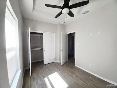 Unfurnished bedroom featuring a closet, wood tiled floors, a ceiling fan, and a raised ceiling