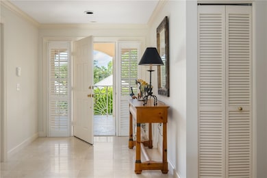 Foyer featuring crown molding and light marble floors
