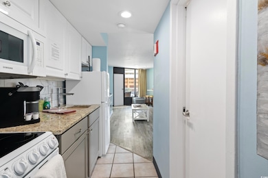 Kitchen with white cabinetry, backsplash, light ti