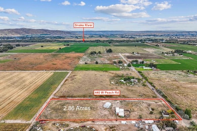 Aerial view of sparsely populated area featuring a mountain backdrop, property parcel outlined, and farmland