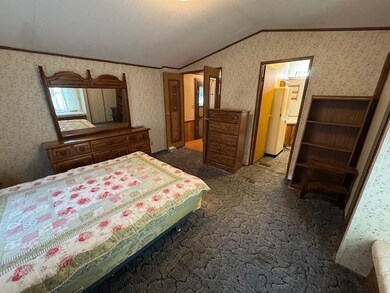 Bedroom featuring vaulted ceiling, ornamental molding, wallpapered walls, and carpet floors