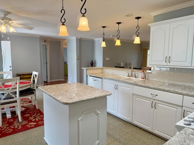 Kitchen with a sink, white dishwasher, crown molding, a ceiling fan, and decorative backsplash