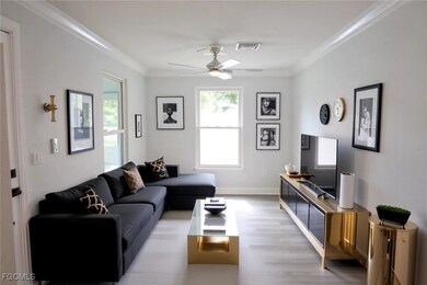 Living room with ornamental molding, plenty of natural light, light wood-style floors, and ceiling fan