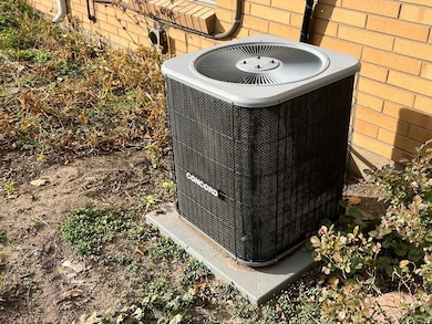 Exterior view of a central AC unit and brick siding
