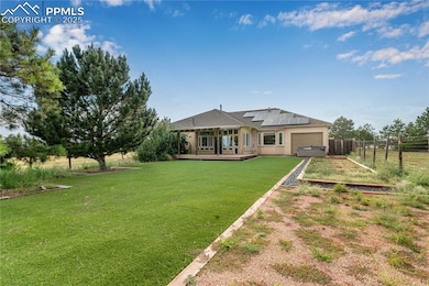 Back of house featuring a wooden deck, solar panels, an attached garage, driveway, and stucco siding