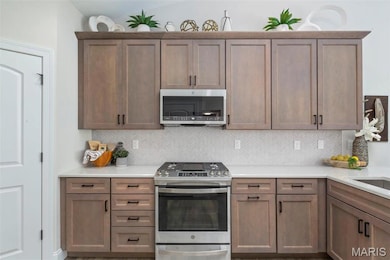 Kitchen with stainless steel appliances and tasteful backsplash