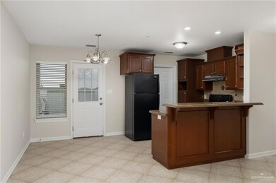 Kitchen featuring a kitchen breakfast bar, kitchen peninsula, black appliances, an inviting chandelier, and tasteful backsplash