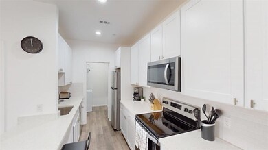Kitchen with white cabinetry, light stone counters
