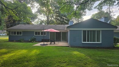 Rear view of property featuring a yard, a chimney, brick siding, and a wooden deck