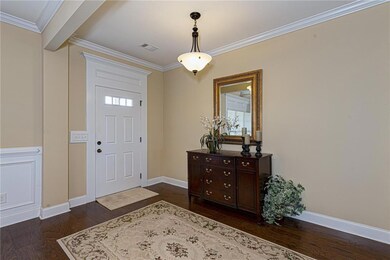 Foyer entrance featuring dark wood-style floors and crown molding
