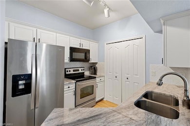 Kitchen with white cabinets, rail lighting, a sink