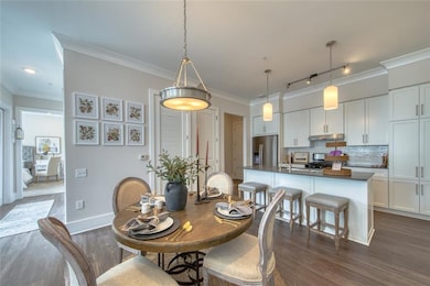 Dining area featuring crown molding, sink, track lighting, and dark hardwood / wood-style floors