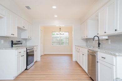 Kitchen with appliances with stainless steel finishes, a chandelier, recessed lighting, light wood-style floors, and decorative backsplash