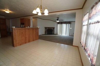 Kitchen featuring ornamental molding, a fireplace, a textured ceiling, pendant lighting, and ceiling fan with notable chandelier