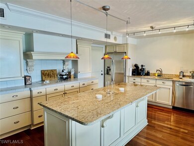 Kitchen featuring appliances with stainless steel finishes, a kitchen island, dark wood-style flooring, and decorative light fixtures