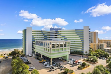 View of property with uncovered parking and view of water and beach