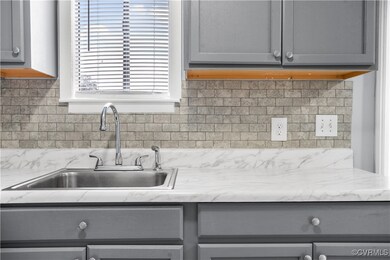 Kitchen featuring gray cabinets, tasteful backsplash, and sink
