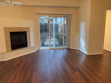 Unfurnished living room with a tile fireplace and dark wood-style flooring
