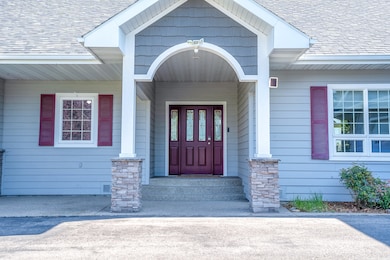 View of exterior entry featuring a shingled roof and covered porch