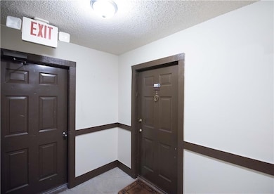 Tiled entrance foyer featuring a textured ceiling and baseboards
