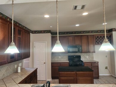 Kitchen featuring tile countertops, black applian
