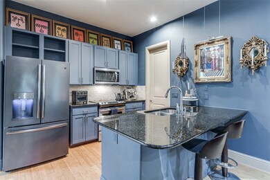 Kitchen with stainless steel appliances, light wood-style floors, decorative backsplash, a breakfast bar area, and a peninsula
