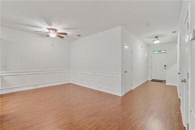 Empty room with a ceiling fan, light wood-style flooring, and wainscoting