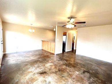 Spare room with finished concrete flooring, a chandelier, and ceiling fan