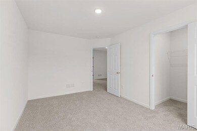 Unfurnished bedroom featuring light colored carpet and a walk in closet