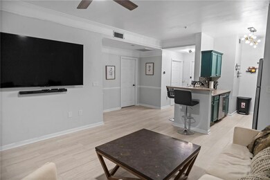 Living room with ceiling fan with notable chandelier, crown molding, and light hardwood / wood-style flooring