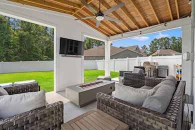 Fenced backyard with an outdoor living space with a fire pit, ceiling fan, and a patio area