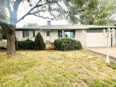 Ranch-style house with an attached garage, concrete driveway, a front yard, a chimney, and brick siding