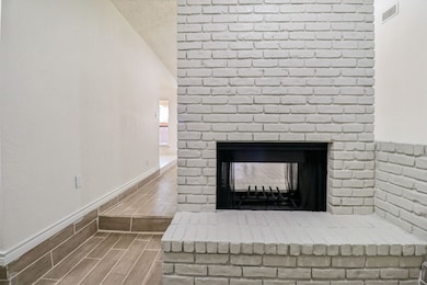 Detailed view of wood tiled floors and a brick fireplace