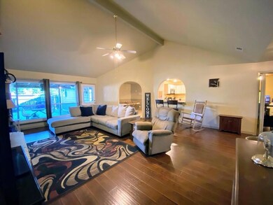 Living room featuring vaulted ceilings, fire place, and ceiling fan over looking covered patio