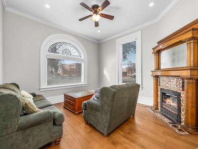 Living room with ornamental molding, light wood finished floors, a ceiling fan, a tile fireplace, and recessed lighting