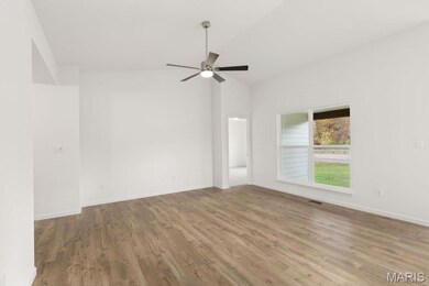 Empty room with wood finished floors, a ceiling fan, and vaulted ceiling