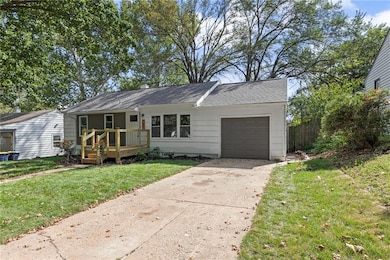 Ranch-style house with a front lawn, a garage, concrete driveway, and a wooden deck
