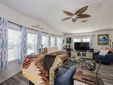 Living area with wood finished floors, vaulted ceiling, and ceiling fan