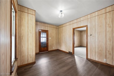 Foyer entrance featuring dark wood-style flooring and baseboards