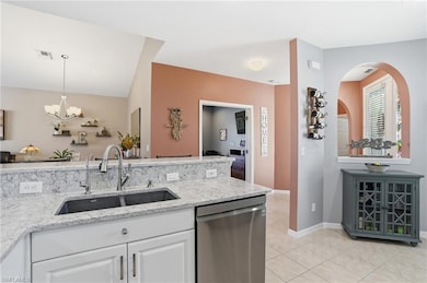 Kitchen with dishwasher, light stone countertops, a chandelier, light tile patterned floors, and decorative light fixtures