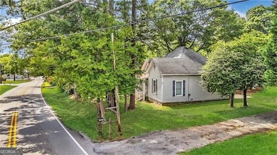 View of side of home with a shingled roof, a lawn, and view of wooded area