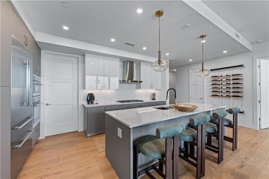 Kitchen with modern cabinets, light wood-style floors, a breakfast bar area, light countertops, and white cabinets